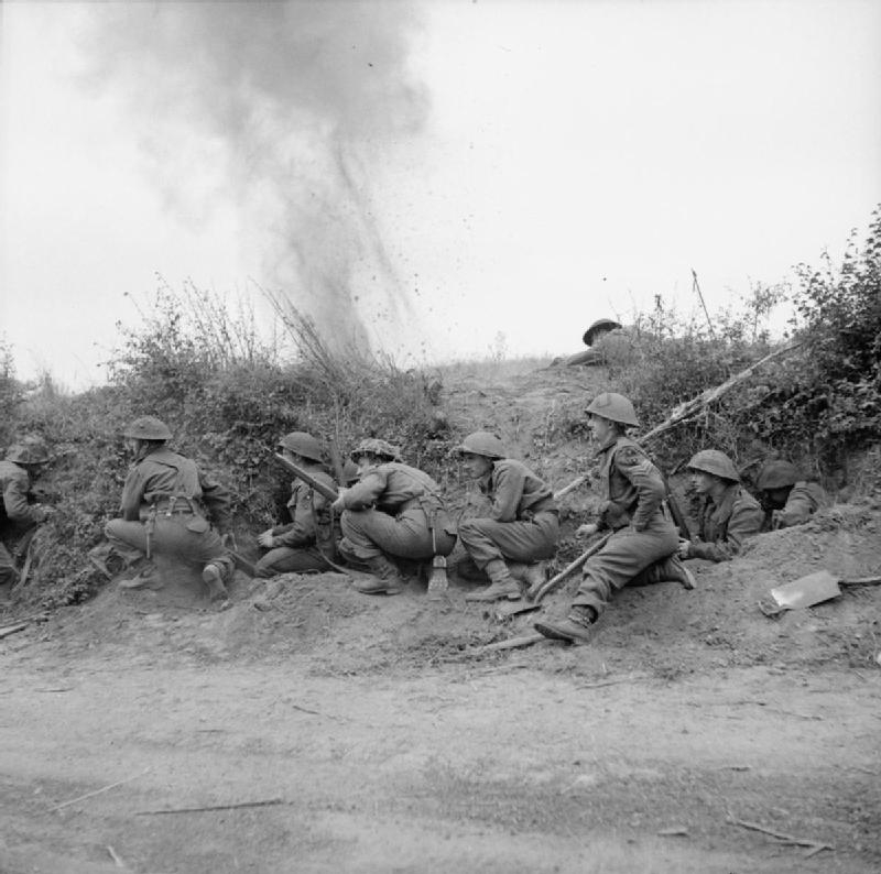 Men of the 2nd Battalion, East Yorkshire Regiment take cover behind a bank as an enemy shell explodes nearby, Normandy, France, 19 July 1944.
